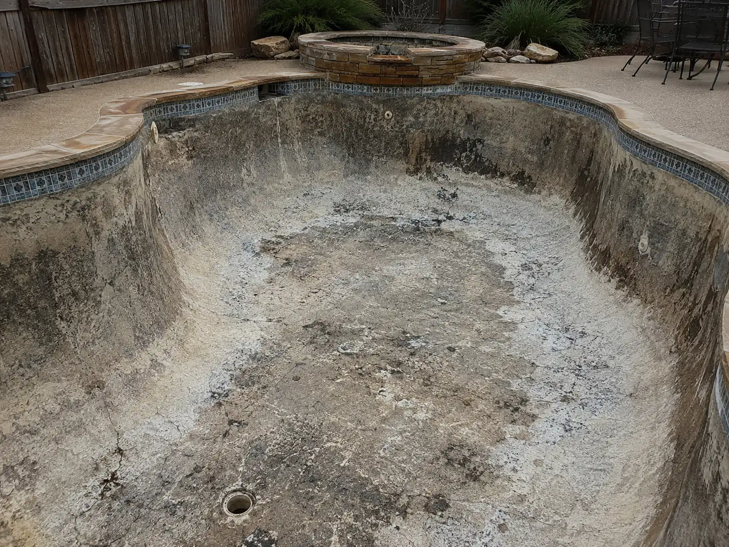 Before: drained pool with worn, stained plaster in North Texas