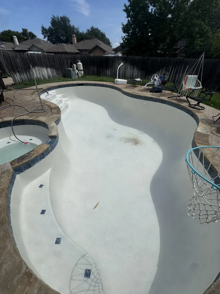 Freeform pool and spa with new white plaster before filling in Irving, TX