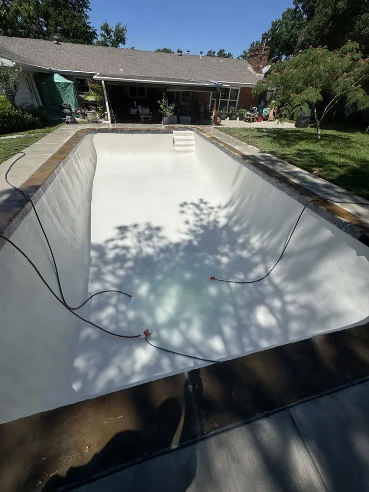 Drained rectangular pool with new white plaster finish in Keller, TX
